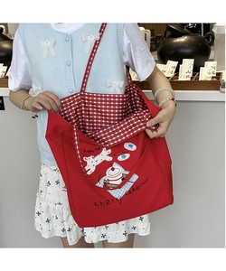 Detail of red canvas tote bag featuring dog illustration and red checkered inner lining