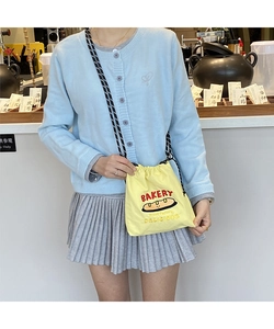 Detail of yellow canvas drawstring bag featuring red Bakery embroidery and cartoon bread