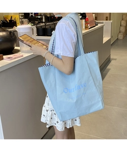Detailed view of spacious light blue canvas tote bag with artistic blue text print