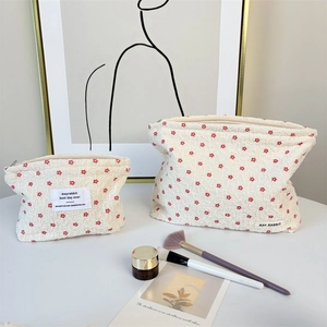 Detail of floral bubble texture fabric on cream cosmetic bags with zipper closure