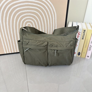 Détail d'un sac bandoulière en nylon vert armée avec multiples poches en décor intérieur