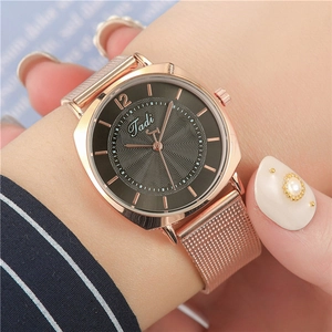 Detail of rose gold mesh watch with grey dial featuring radial texture on female wrist