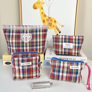 Detail of four-piece plaid makeup bag set with lace trim and durable canvas material