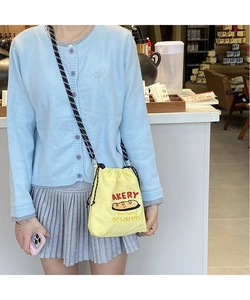 Detail of yellow canvas drawstring bag with red bakery text and woven shoulder strap