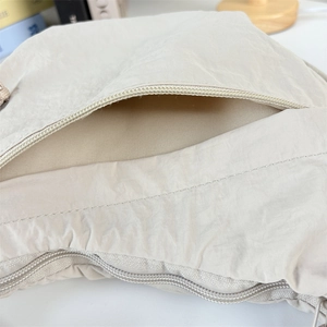 Close-up of exterior zip pocket and pleated nylon texture on a minimalist hobo bag