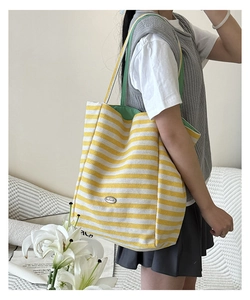 Détail d'un sac cabas en toile rayé jaune et blanc avec boucle en métal et bandoulière