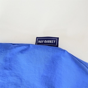 Gros plan sur l'étiquette May Rabbit cousue sur un tissu en nylon bleu imperméable