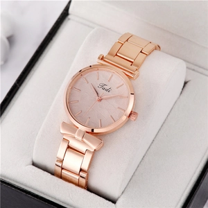 Detail of rose gold watch featuring leaf texture dial and bow-shaped decorative lugs