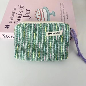Detail der gewebten Mini-Kosmetiktasche mit lila Kordelgriff und bunten Streifenmustern