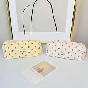 Close-up of seersucker makeup bag with red floral embroidery and metal zipper texture