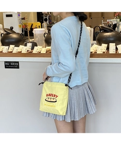 Detail of yellow canvas bakery bag with red lettering and woven shoulder strap