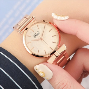 Close-up of a women's rose gold watch with leaf pattern dial on a female wrist
