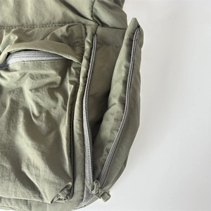 Vue détaillée du sac bandoulière en nylon vert armée avec poche zippée et texture de tissu