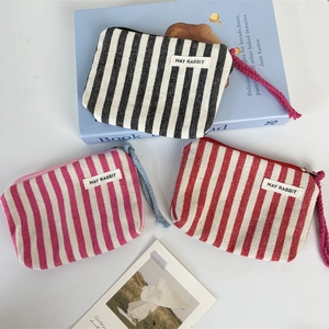 Detailed top view of striped canvas coin purses with fabric labels and braided zipper pulls