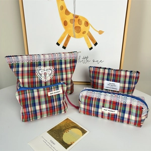 Detail of tartan cosmetic bag set featuring white lace trim and bow embroidery