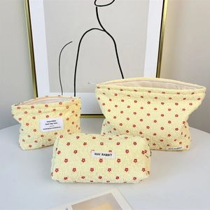 Three-piece yellow seersucker makeup bag set with red floral patterns and zip closure