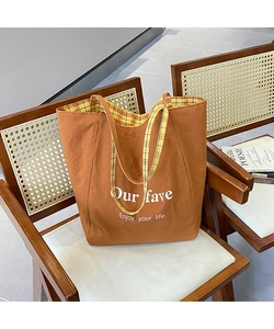 Close-up of brown canvas tote bag with grid lining and motivational text on wooden chair