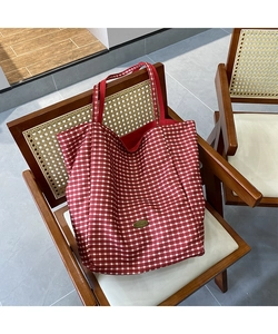 Close-up of handmade metal logo on red checkered tote bag with high quality fabric texture