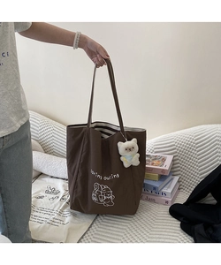 Détail du cabas marron avec imprimé ours, doublure rayée et pendentif chat en peluche
