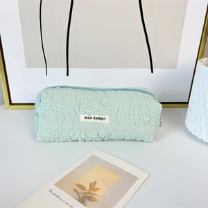 Close-up of mint green pleated fabric pencil case with May Rabbit woven label