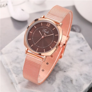 Detail of rose gold mesh strap watch with a textured brown dial on a marble stand