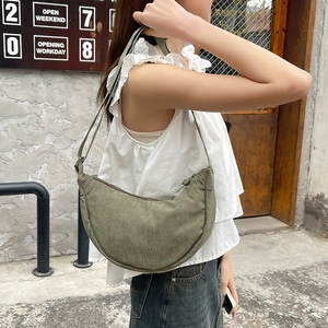 Detail showing the gray-green corduroy texture and adjustable strap of the crescent bag