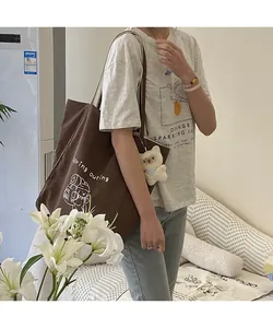 Vue détaillée du grand sac fourre-tout en toile marron avec imprimé ours et breloque