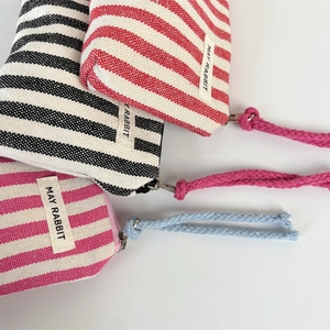 Detail of colorful striped canvas coin purses with woven logo and rope zipper pullers