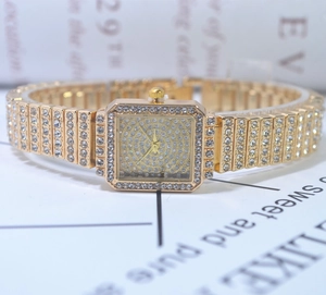 Macro view of luxury square quartz watch with full rhinestone accents on gold metal strap