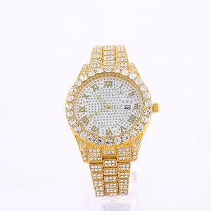 Macro view of gold iced-out watch with crystal bezel, roman numerals, and date window