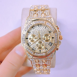 Close-up of luxury gold-tone watch face featuring roman numerals and crystal pavé details