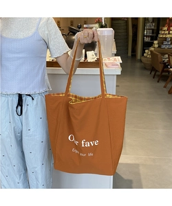 Detailed view of the brown canvas tote bag with check lining and white text slogans