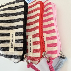 Three striped canvas coin purses in red, pink, and black with woven zip pulls