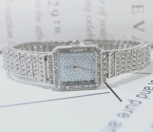 Macro detail of silver square quartz watch featuring full diamond rhinestones and steel band