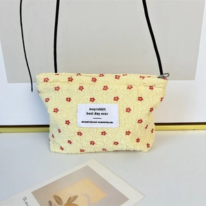 Detail of yellow popcorn fabric makeup bag with red floral print and stylish woven label