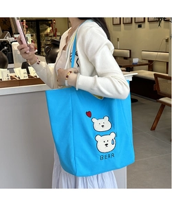 Detail of blue canvas tote bag featuring cute white bear embroidery and red heart