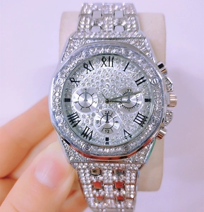 Macro shot of silver diamond-encrusted watch with three-eye dial and Roman numerals