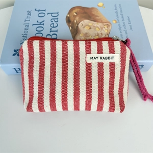Detail of red and white striped canvas coin purse with zipper and May Rabbit label