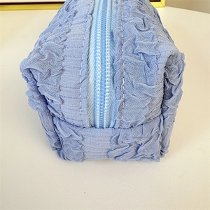 Close-up of light blue pleated mesh storage bag with zipper and portable handle strap