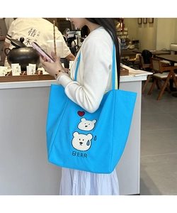 Detailed close-up of blue canvas tote bag featuring cute bear embroidery and text