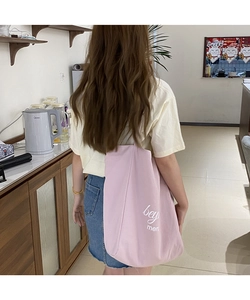 Vue lifestyle d'un sac cabas en toile rose avec texte blanc porté sur l'épaule