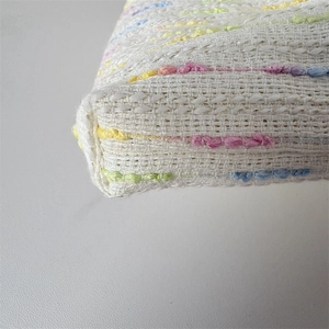 Detailansicht der gewebten Textur mit bunten Pompons und präziser Naht an der Ecke