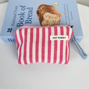 Detail of pink striped canvas coin purse with zipper closure and blue wrist strap