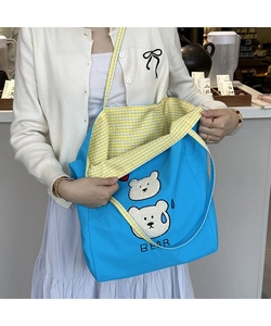 Detail of blue canvas tote bag featuring bear embroidery and yellow checkered lining