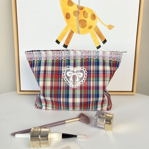 Detail of plaid makeup bag with heart lace patch, bow embroidery and white lace trim