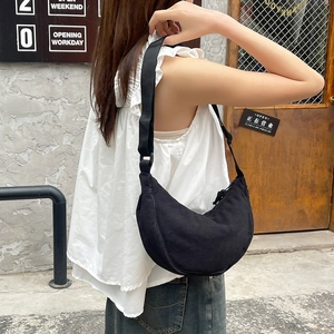 Detail of black corduroy crescent bag showing fabric texture and adjustable shoulder strap