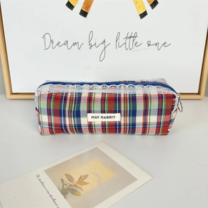 Detail of red and blue plaid makeup bag with white lace trim and May Rabbit label