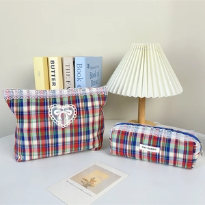 Detailed view of plaid cosmetic bags with white lace edges and heart ribbon applique