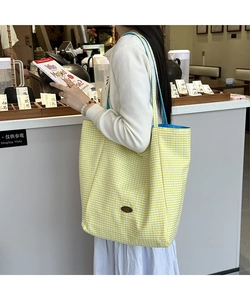 Detail of yellow gingham tote bag with blue interior lining and leather logo patch