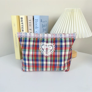 Close-up of sweet plaid makeup bag featuring white lace edges and heart bow detail